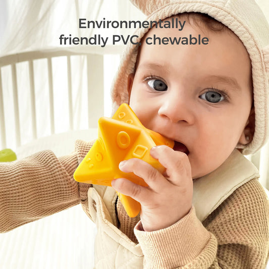 A baby wearing a beige outfit and hat chews on a bright yellow star-shaped sensory toy made from environmentally friendly PVC. The toy features raised textures and geometric shapes for tactile stimulation. The text "Environmentally friendly PVC chewable" appears at the top, emphasizing the toy’s safety and eco-friendly design.