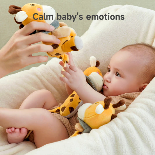 A baby lies comfortably on a soft cushion while holding and interacting with plush giraffe rattles. An adult hand gently offers one of the giraffe toys to the baby, who looks calm and focused. The text “Calm baby’s emotions” appears at the top, highlighting the toy’s soothing effect.