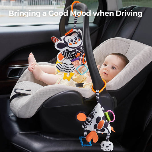 Baby sitting in a car seat, playing with hanging black and white high-contrast sensory toys attached to the handle. The plush cubes feature animal prints, colorful teethers, rattles, and textured accessories, keeping the baby entertained and calm during travel.