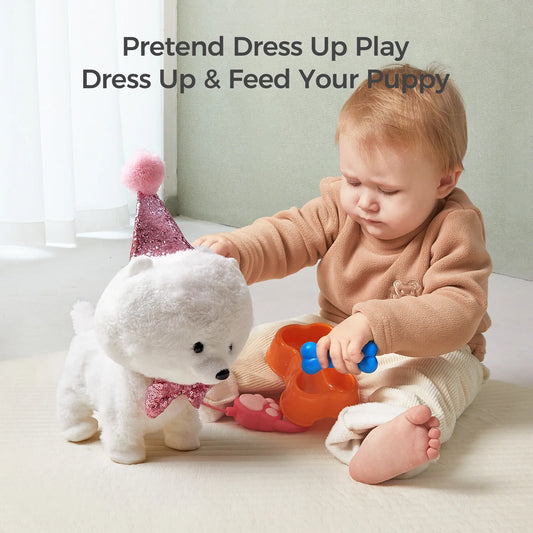 Toddler playing with a white interactive toy dog wearing a glittery pink party hat and bow tie. The child is pretending to feed the puppy using a blue bone-shaped toy and orange feeding bowl. Pretend play activity encourages imagination.
