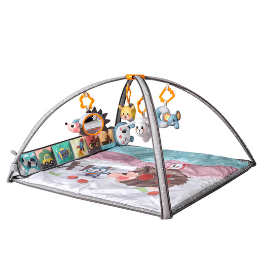 Colorful baby play gym with soft padded mat, two grey arches, and five hanging plush rattles including a hedgehog with mirror, cat, cow, lamb, and elephant. Side cloth book panel with colorful illustrations adds interactive play.