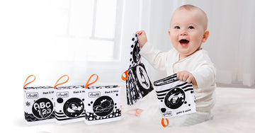 Image of a baby happily reading a high contrast black and white book