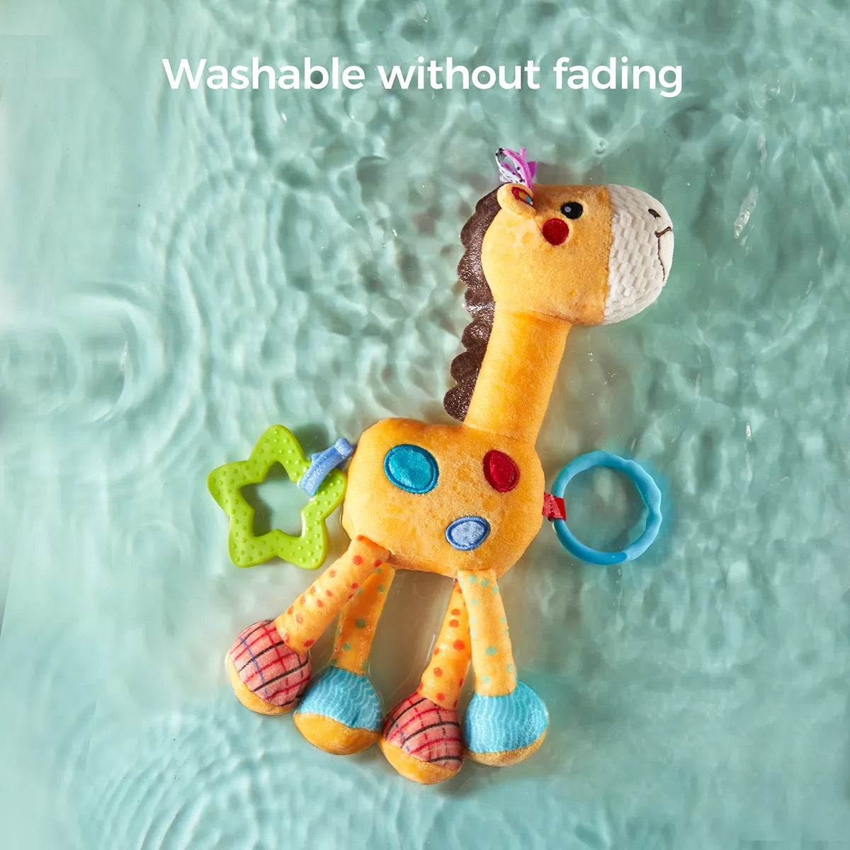 Plush giraffe baby toy floating in clear water, demonstrating its washable design. The toy features bright colors, teething rings, and textured fabrics. Text at the top reads “Washable without fading,” emphasizing its durability and easy maintenance.