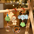 Close-up of three detachable plush hanging toys—a tree with rattle, smiling lion, and blushing elephant with a green teether—suspended from orange rings on a wooden play gym, with an inset showing the snap-on ring design for easy attachment and removal.