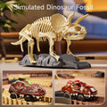 Close-up of a simulated dinosaur fossil model of a Triceratops displayed on a gray platform, with two toy dinosaur cars shown below — one battery-operated and one featuring LED lights, both on a flexible racetrack.